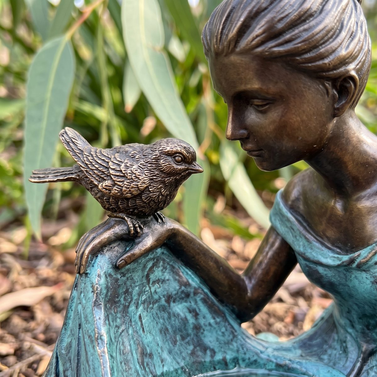 Close-up of the small cast bronze bird on her hand