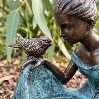 Close-up of the small cast bronze bird on her hand