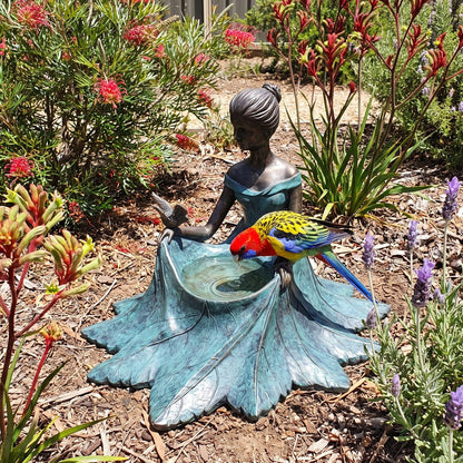 Bronze bird bath among native plants with a rosella drinking