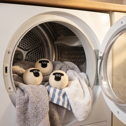 Three sheep wool dryer balls in a tumble dryer drum with towels