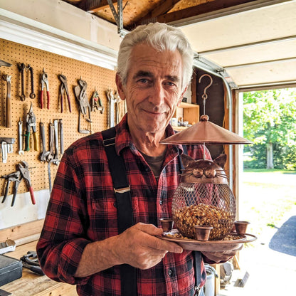 Michael holding a finished cat-faced bird feeder in his garage