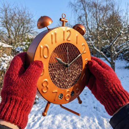 Copper clock bird feeder held in two hands for size