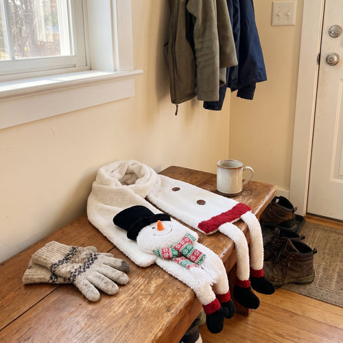 Snowman Christmas scarf with dangling boots on a mudroom bench