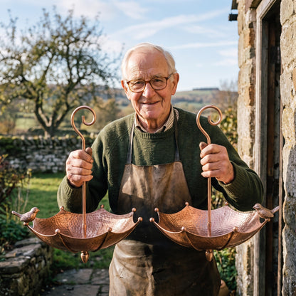 Dudley Tunnicliffe holding two of his copper umbrella feeders at the forge door