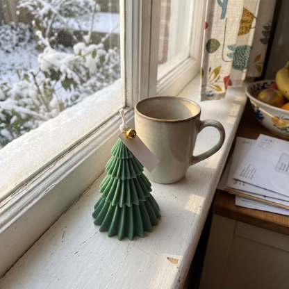 Green Fraser Tree candle on a snowy windowsill