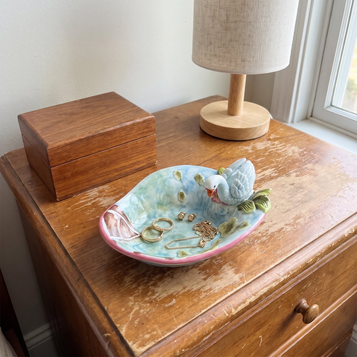 Swan dish holding rings and jewelry on a dresser