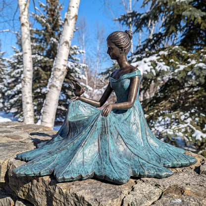 Side view of the bronze leaf-maiden bird bath on a fieldstone wall