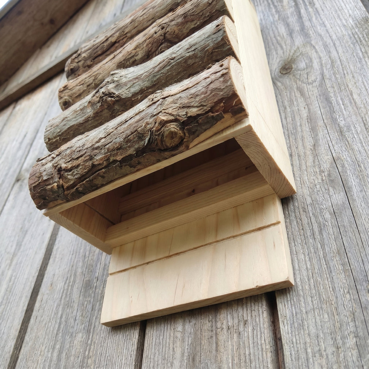 Low-angle view showing the open-bottom entry and landing board where bats climb in