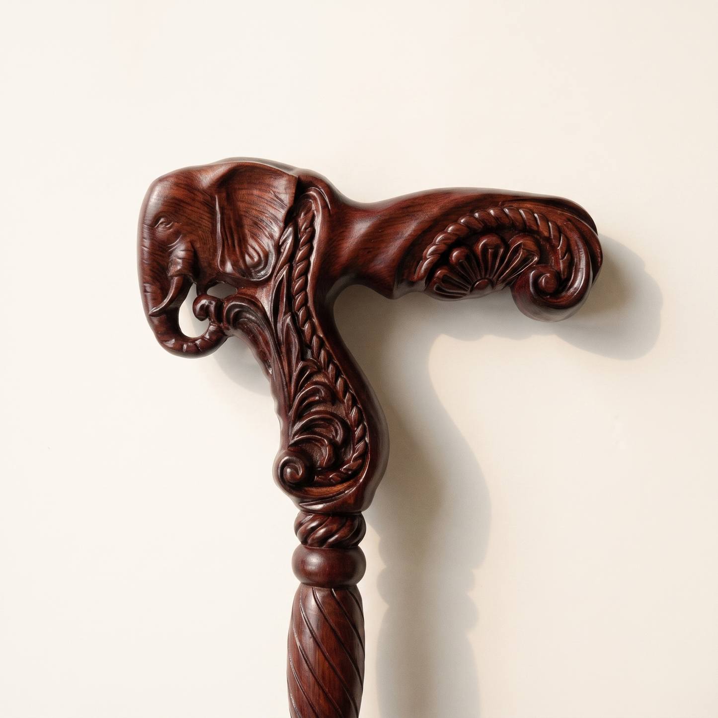 Close-up of the carved elephant head grip in burgundy rosewood with curled trunk and scrollwork