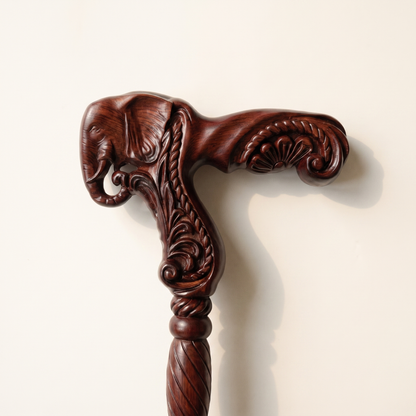Close-up of the carved elephant head grip in burgundy rosewood with curled trunk and scrollwork