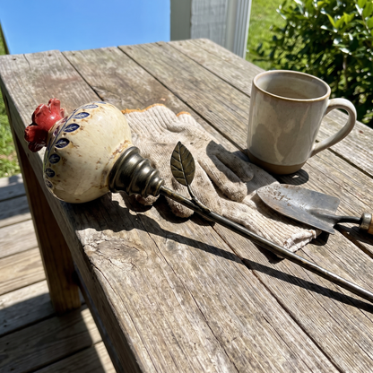 Feeder on a porch table next to a mug and garden tools