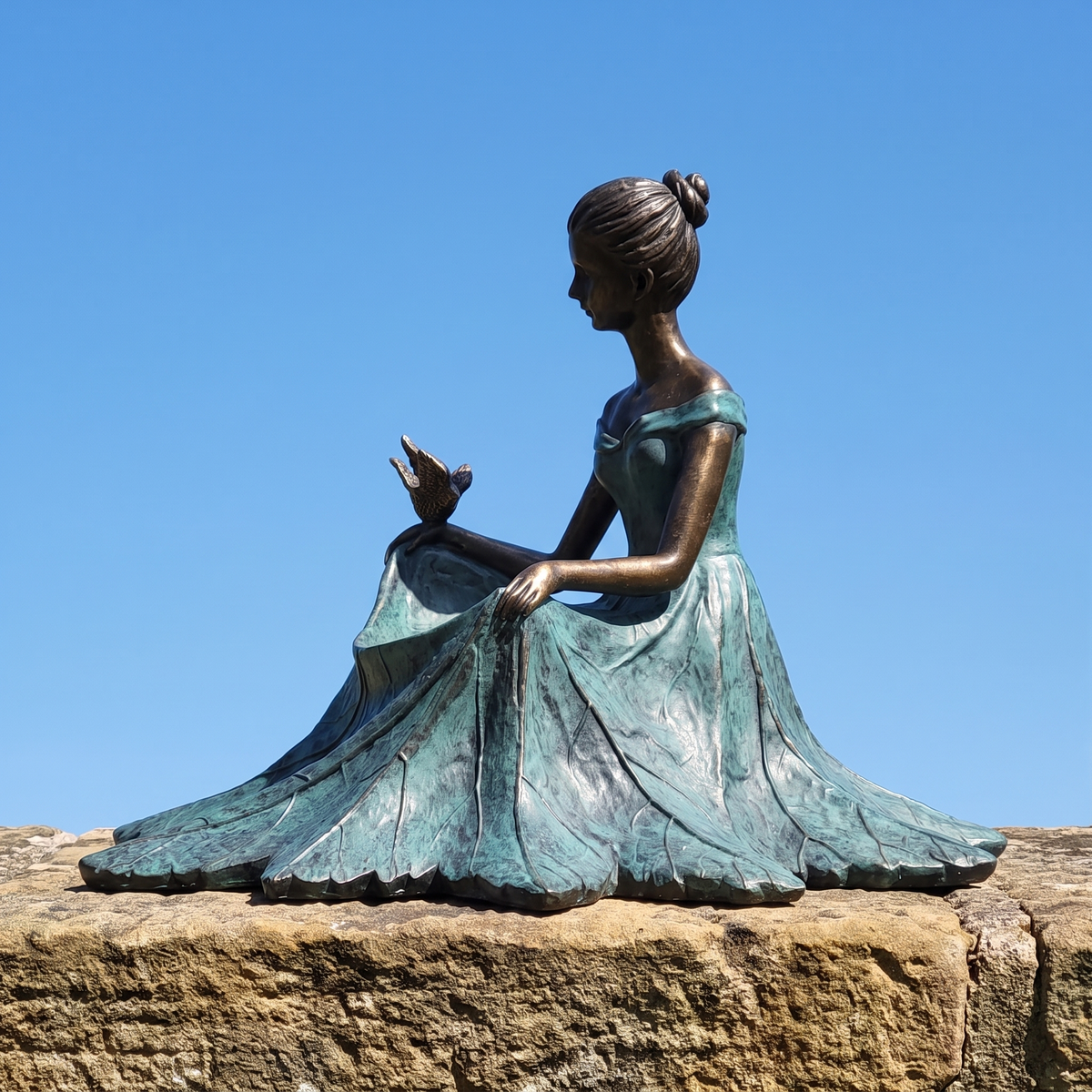 Side profile of the bird bath statue on an old sandstone wall