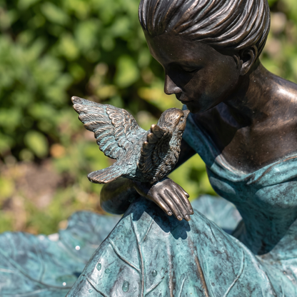 Close-up of the small cast bronze bird on the girl's hand