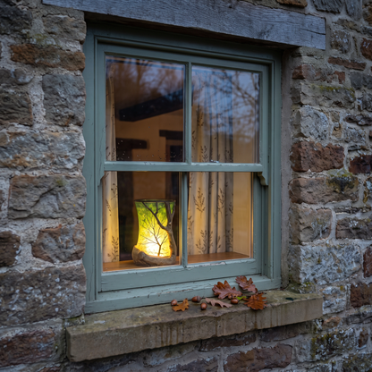 Alwyn's Oak Lantern glowing in a cottage window at dusk