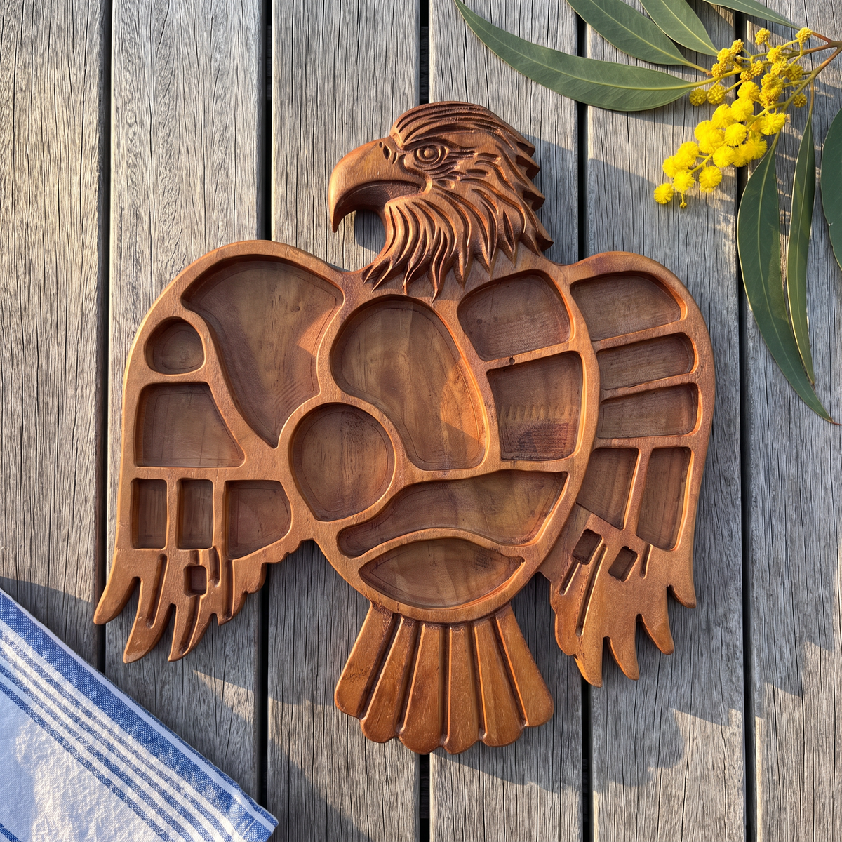 Hand-carved Eagle serving tray on hardwood decking with wattle
