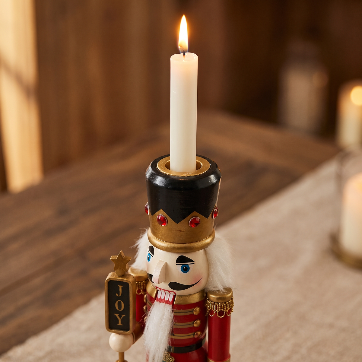 Close-up of the painted nutcracker's hat holding a taper candle, gold crown with red jewels and JOY sign