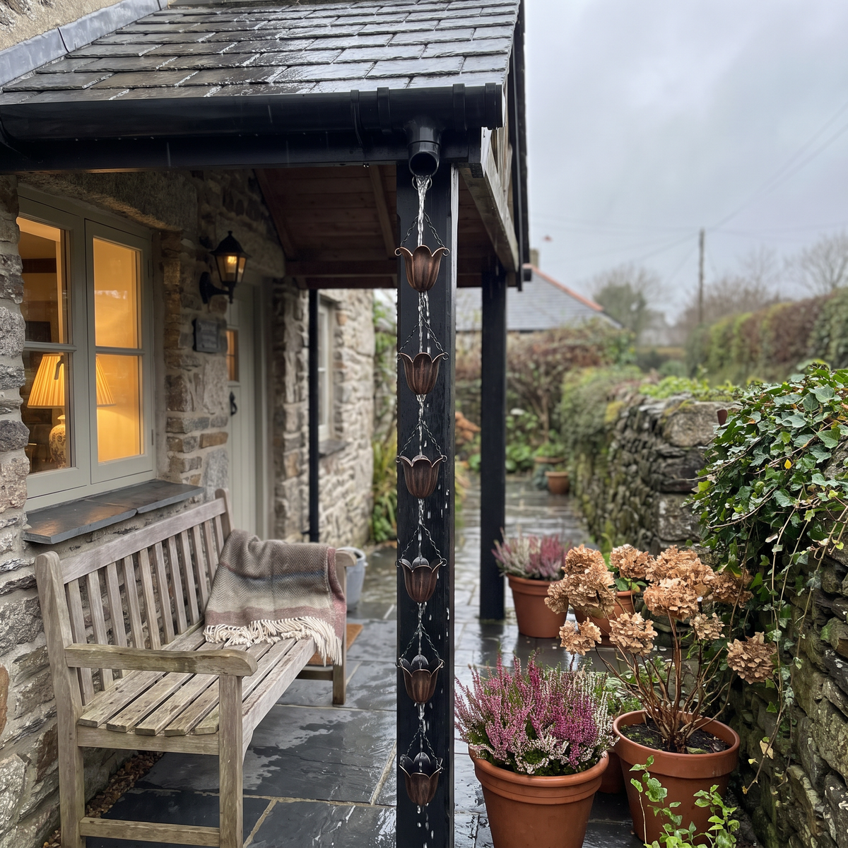 Aldous's copper tulip rain chain hanging from a cottage gutter in the rain
