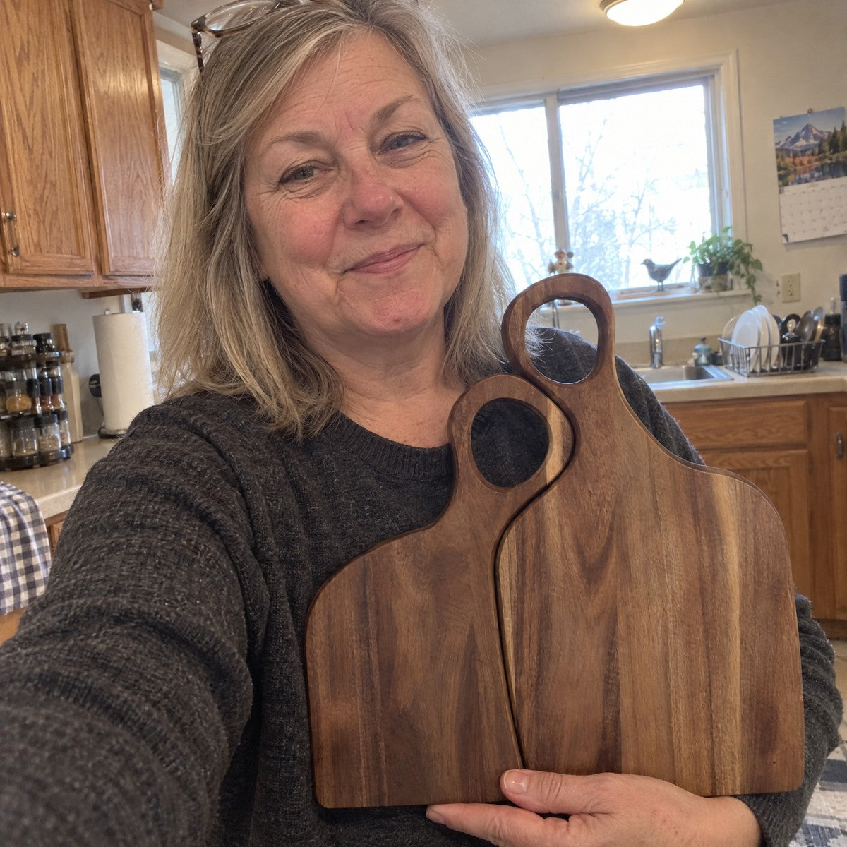 Customer selfie holding both walnut boards in her kitchen