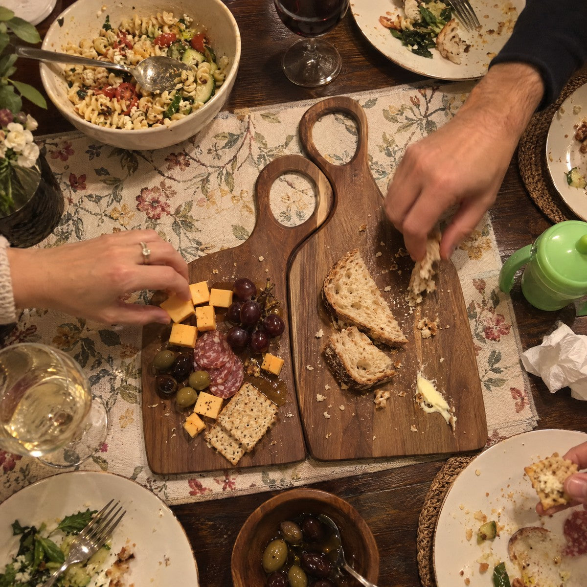 Both walnut boards on a family dinner table with cheese and bread