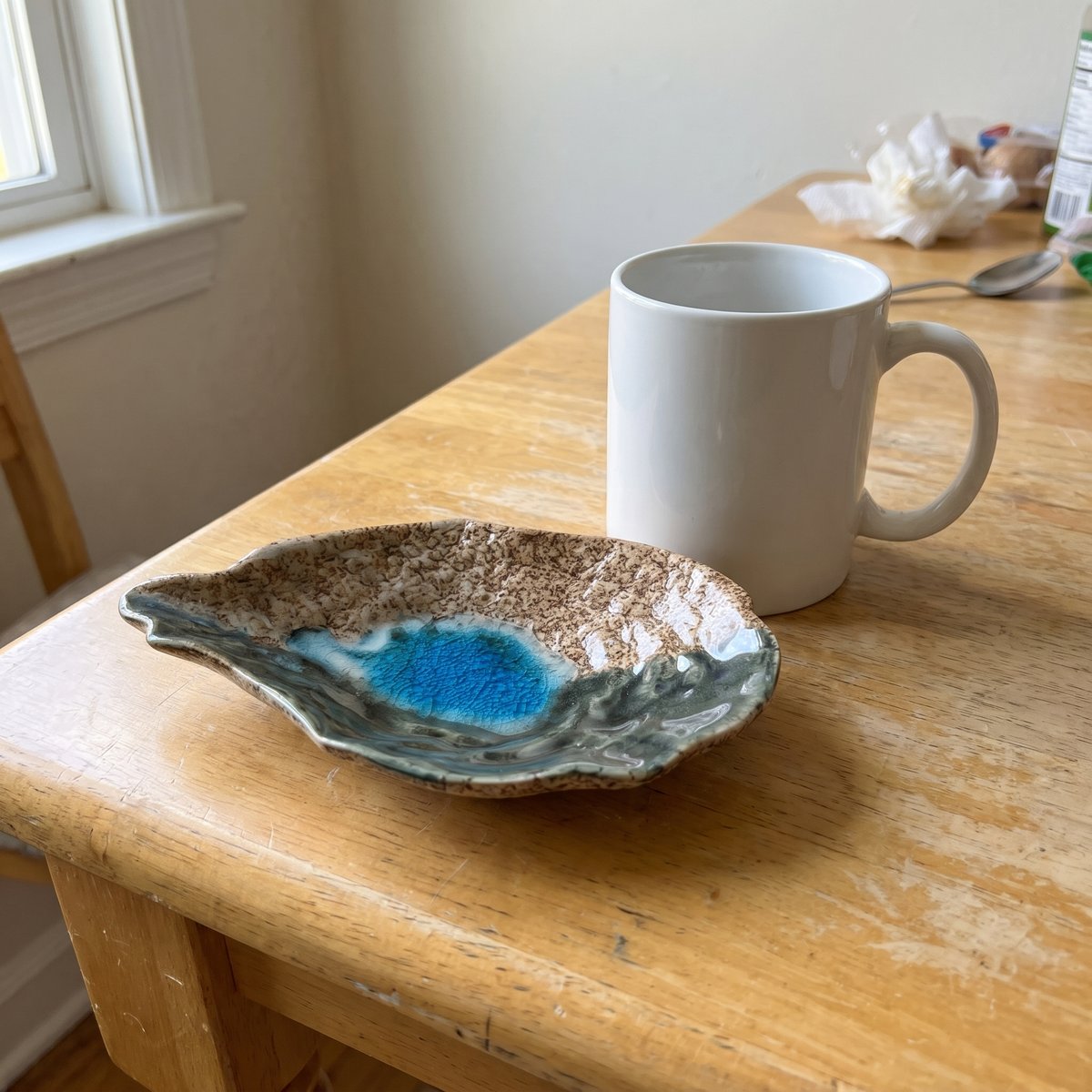 Duane's oyster shell plate in Cat Point Sand glaze next to a coffee mug