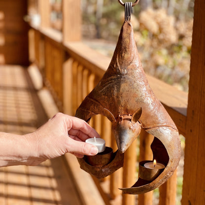 Placing a tea light into the wing cup of the iron bat lantern