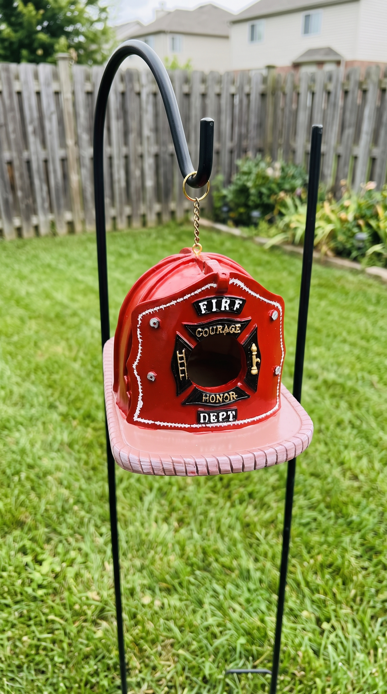 Firefighter helmet birdhouse on a backyard hook