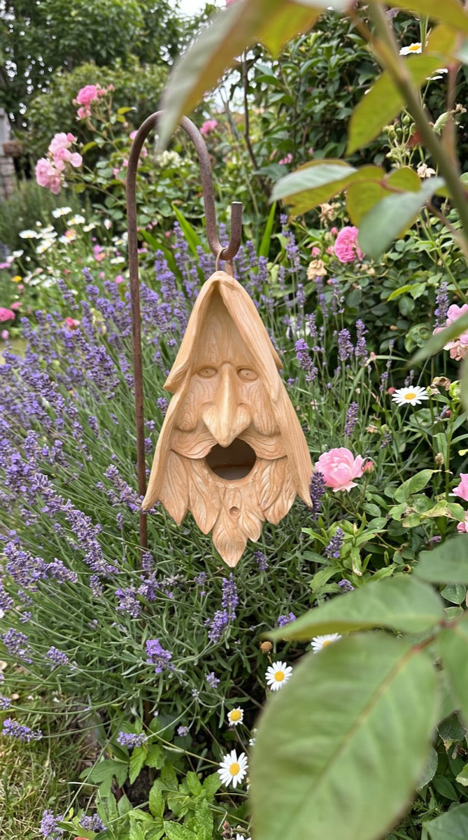 Wood-spirit birdhouse in a lavender flower border